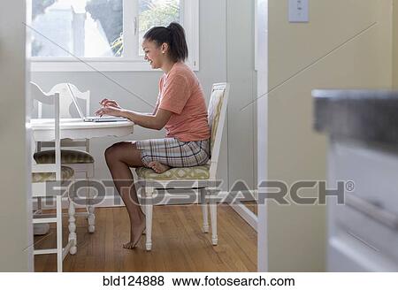 Stock Photo - Mixed race woman using laptop at table. Fotosearch