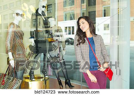 Stock Image - Mixed race woman window shopping in city. Fotosearch