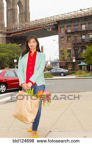 Stock Photo - Mixed race woman with shopping bag, New York, New York, United States. Fotosearch