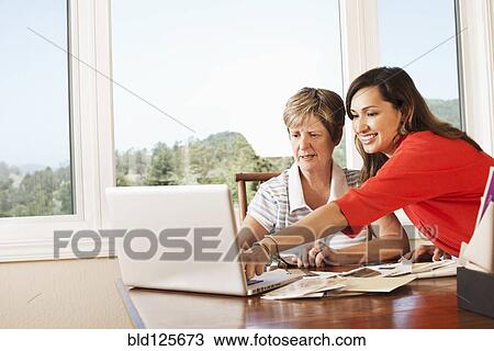 Mother and daughter using laptop at desk View Large Photo Image Stock Image - Mother and daughter using laptop at desk. Fotosearch