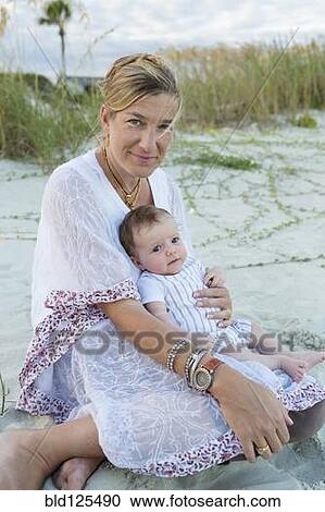 Stock Image - Mother cradling newborn boy on beach. Fotosearch