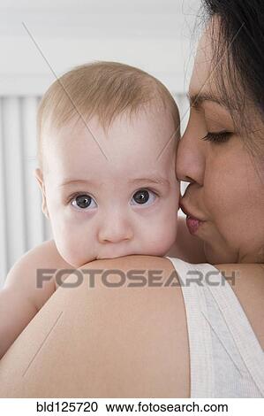 Stock Image - Mother kissing Hispanic baby boy's cheek. Fotosearch