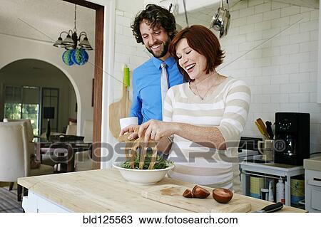 Stock Image - Pregnant Caucasian couple cooking in kitchen. Fotosearch