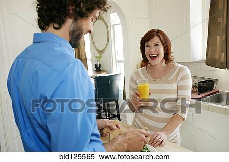 Stock Photography - Pregnant Caucasian couple cooking in kitchen. Fotosearch