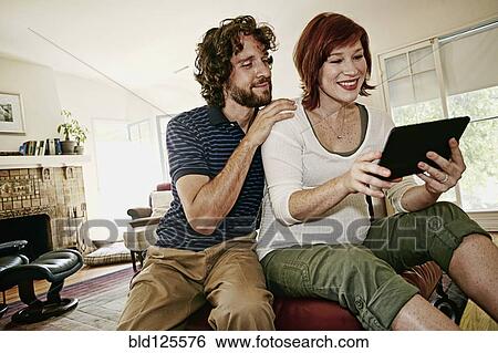Stock Photograph - Pregnant Caucasian couple using digital tablet. Fotosearch