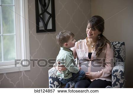 Stock Photo - Pregnant Caucasian mother sitting with son. Fotosearch