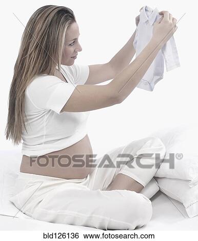 Pregnant Caucasian woman folding baby clothes View Large Photo Image Stock Photograph - Pregnant Caucasian woman folding baby clothes. Fotosearch
