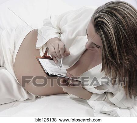 Stock Photo - Pregnant Caucasian woman writing in planner. Fotosearch