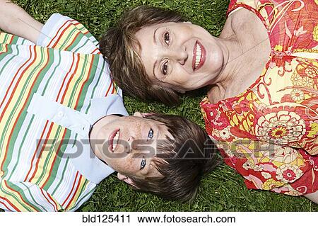 Stock Image - Senior Caucasian woman and grandson laying in grass. Fotosearch