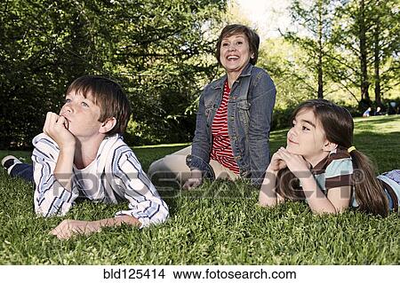 Picture - Senior Caucasian woman and grandchildren sitting in park. Fotosearch