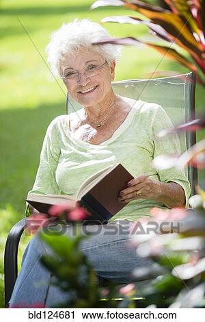 Senior Caucasian woman reading book outdoors View Large Photo Image Stock Image - Senior Caucasian woman reading book outdoors. Fotosearch