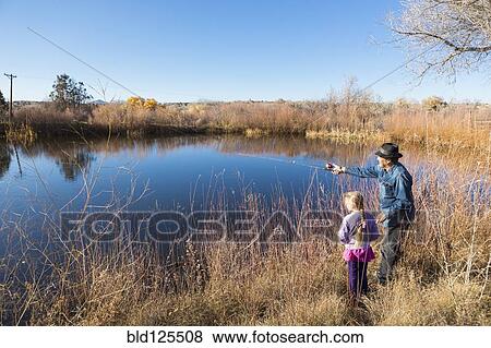 Stock Photo - Senior man and granddaughter watching calm lake. Fotosearch