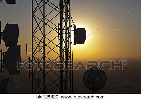 Stock Image - Silhouette of communications tower against sunset sky. Fotosearch