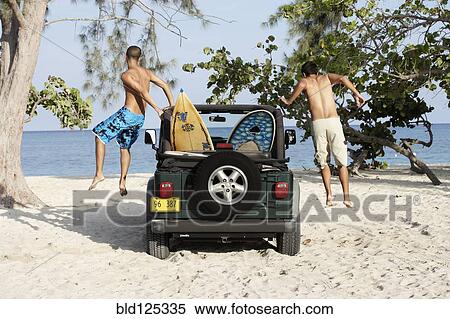Surfers jumping out of 4x4 with surfboards on beach View Large Photo Image Stock Photography - Surfers jumping out of 4x4 with surfboards on beach. Fotosearch