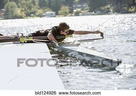 Stock Photograph - Teenage boy preparing scull from dock over lake. Fotosearch