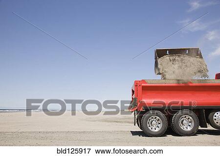 Stock Photo - Truck shoveling sand on beach. Fotosearch