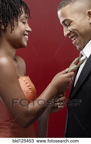 Stock Image - Woman in dress adjusting man's tie. Fotosearch