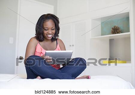 Woman using digital tablet on bed View Large Photo Image Stock Photography - Woman using digital tablet on bed. Fotosearch