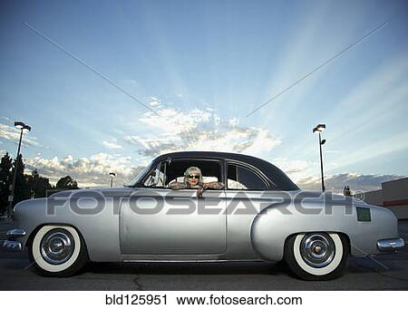 Stock Image - Woman with tattoos leaning out window of 1951 Chevy. Fotosearch