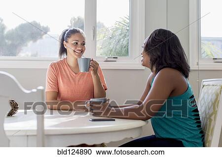 Stock Image - Women drinking coffee together at table. Fotosearch