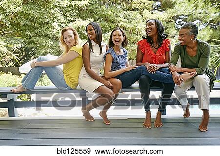 Stock Photo - Women smiling together on bench. Fotosearch