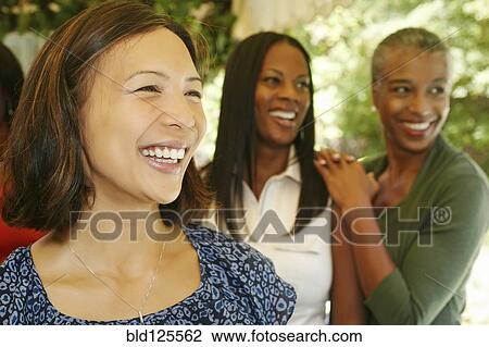 Stock Image - Women smiling together on patio. Fotosearch
