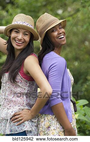 Stock Image - Women standing back to back outdoors. Fotosearch