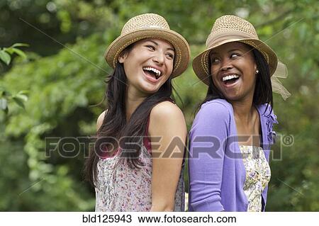 Stock Image - Women standing back to back outdoors. Fotosearch
