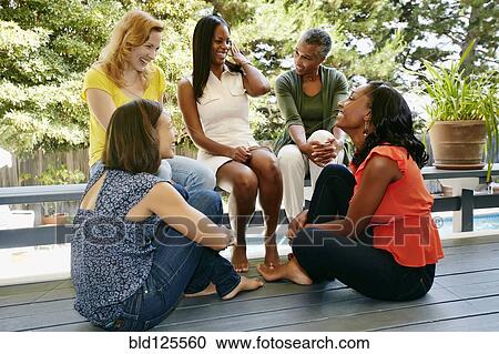 Stock Image - Women talking on patio. Fotosearch