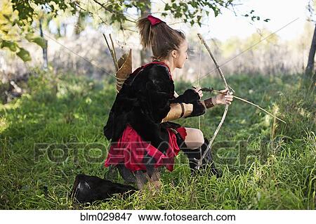 Stock Photo - Caucasian girl in costume holding bow and arrow. Fotosearch