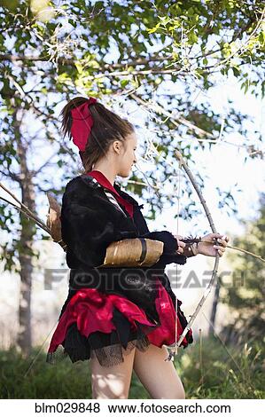 Stock Photo - Caucasian girl in costume with bow and arrow. Fotosearch