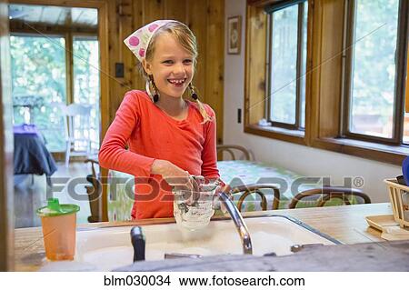 Picture - Caucasian girl washing dishes in kitchen. Fotosearch