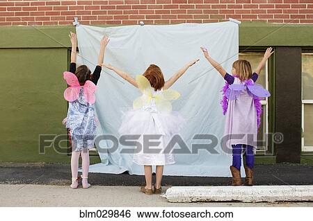 Stock Photograph - Caucasian girls in fairy costumes pretending to fly. Fotosearch