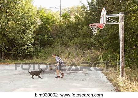 Stock Image - Caucasian man playing basketball with dog. Fotosearch