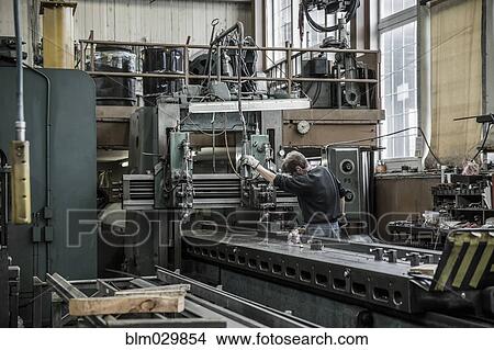 Picture - Caucasian man using machinery in metal shop. Fotosearch