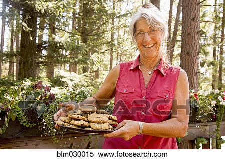 Stock Photography - Caucasian woman holding plate of cookies on balcony. Fotosearch
