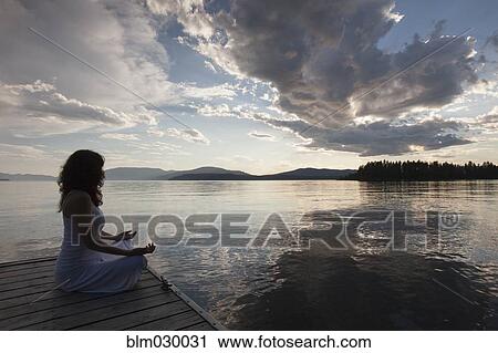 Caucasian woman meditating on wooden dock in still lake View Large Photo Image Stock Image - Caucasian woman meditating on wooden dock in still lake. Fotosearch