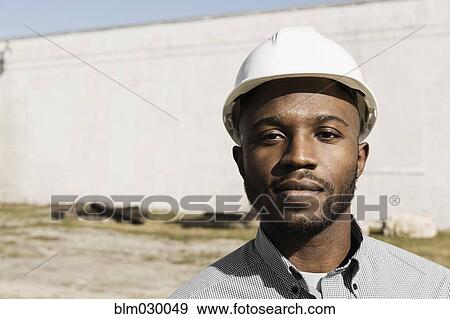 Stock Photo - Close up portrait of Black man wearing hard-hat at construction site. Fotosearch