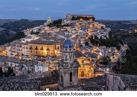Stock Image - Hilltop town illuminated at dusk, Ragusa Ibla, Sicily, Italy. Fotosearch