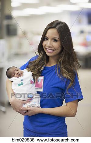 Stock Photo - Nurse holding newborn baby in hospital. Fotosearch
