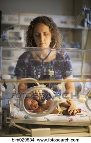 Picture - Nurse tending to newborn in incubator. Fotosearch