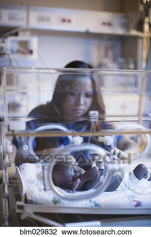 Stock Image - Nurse tending to newborn in incubator. Fotosearch