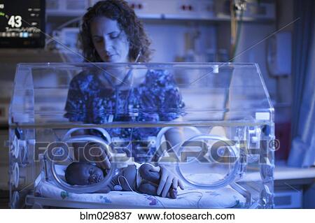 Stock Photo - Nurse tending to newborn in incubator. Fotosearch