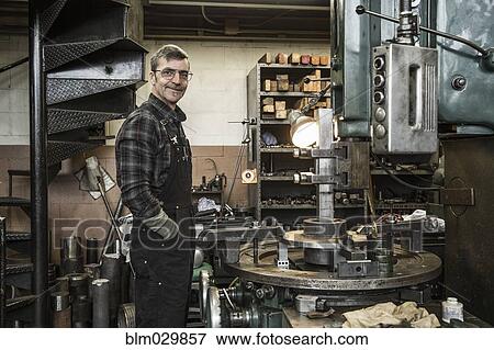Stock Photo - Portrait of Caucasian man smiling in metal shop. Fotosearch