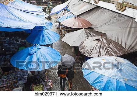 Stock Image - Rain falling over tarps and awnings of market stalls, Ubud, Bali, Indonesia. Fotosearch