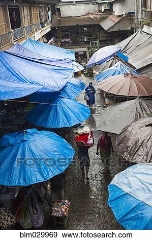 Stock Photo - Rain falling over tarps and awnings of market stalls, Ubud, Bali, Indonesia. Fotosearch