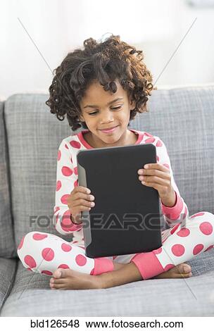 African American girl in pajamas using digital tablet on sofa View Large Photo Image Stock Photo - African American girl in pajamas using digital tablet on sofa. Fotosearch