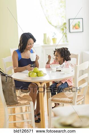 Stock Image - African American mother and daughter at breakfast table. Fotosearch