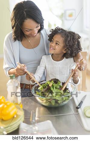 Picture - African American mother and daughter tossing salad. Fotosearch
