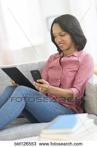 Stock Image - African American using cell phone and digital tablet. Fotosearch
